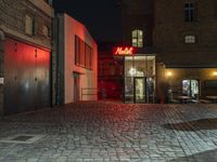 a bricked alley and a red neon sign are pictured in this photo and the buildings look to be empty