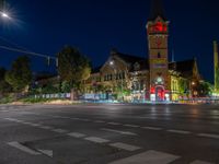 a night scene with traffic lights shining at an intersection with a church in the background