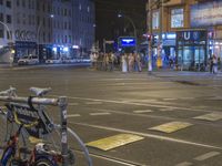 there is a bicycle parked in the street at night time at the corner of the intersection