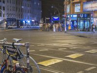 there is a bicycle parked in the street at night time at the corner of the intersection