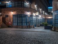 some dark blue windows in an industrial building with no one on the street to the right