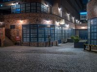 some dark blue windows in an industrial building with no one on the street to the right