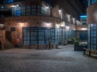 some dark blue windows in an industrial building with no one on the street to the right