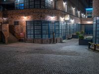 some dark blue windows in an industrial building with no one on the street to the right
