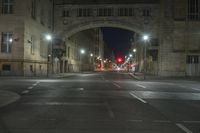 an empty street filled with traffic at night with many lights shining off of the buildings