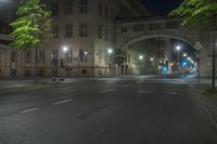 an empty street filled with traffic at night with many lights shining off of the buildings