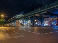 the empty street is filled with people walking and biking under an overpass at night