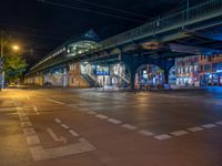 the empty street is filled with people walking and biking under an overpass at night