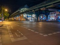 the empty street is filled with people walking and biking under an overpass at night