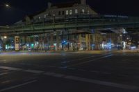 this is a street intersection with traffic lights at night and pedestrian crossing on the bridge