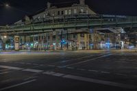 this is a street intersection with traffic lights at night and pedestrian crossing on the bridge