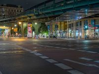 the empty street is filled with people walking and biking under an overpass at night