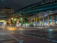 the empty street is filled with people walking and biking under an overpass at night