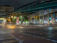 the empty street is filled with people walking and biking under an overpass at night