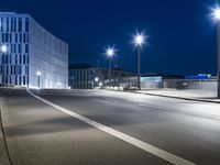 large building on the street with lights in front and other buildings nearby at night with no one moving