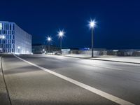 large building on the street with lights in front and other buildings nearby at night with no one moving