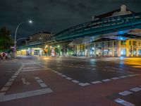 the empty street is filled with people walking and biking under an overpass at night