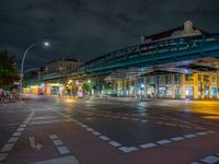 the empty street is filled with people walking and biking under an overpass at night