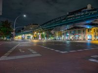 the empty street is filled with people walking and biking under an overpass at night