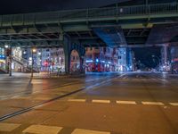 the empty street is filled with people walking and biking under an overpass at night