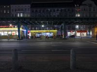 an intersection in a city at night, with cars on the road and buildings behind it