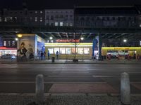 an intersection in a city at night, with cars on the road and buildings behind it