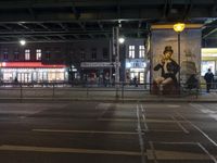 an intersection in a city at night, with cars on the road and buildings behind it