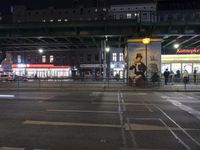 an intersection in a city at night, with cars on the road and buildings behind it