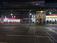 an intersection in a city at night, with cars on the road and buildings behind it