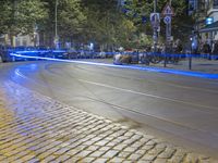 a street corner with cars and some lights and people on the sidewalk waiting to cross the road