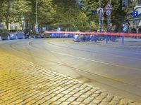 a street corner with cars and some lights and people on the sidewalk waiting to cross the road