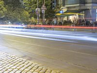 a street corner with cars and some lights and people on the sidewalk waiting to cross the road