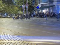 a street corner with cars and some lights and people on the sidewalk waiting to cross the road