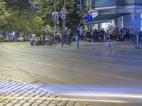 a street corner with cars and some lights and people on the sidewalk waiting to cross the road