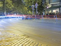 a street corner with cars and some lights and people on the sidewalk waiting to cross the road