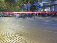 a street corner with cars and some lights and people on the sidewalk waiting to cross the road