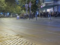 a street corner with cars and some lights and people on the sidewalk waiting to cross the road