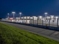 the airport terminal has lots of hangars at night with parking spaces in front of them