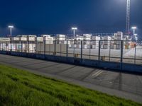 the airport terminal has lots of hangars at night with parking spaces in front of them