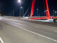 a red bridge and lights at night with no one in sight for it to pass