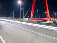 a red bridge and lights at night with no one in sight for it to pass