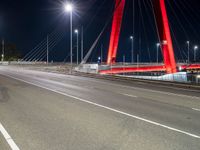 a red bridge and lights at night with no one in sight for it to pass