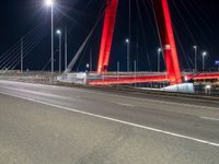 a red bridge and lights at night with no one in sight for it to pass