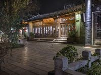 the front door and entrance of a chinese building at night, at an intersection with a lot of greenery