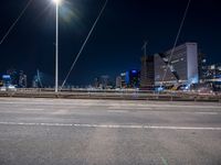 a road with buildings in the distance near by in a city at night time with full moon