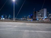 a road with buildings in the distance near by in a city at night time with full moon