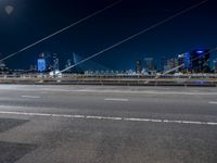 a road with buildings in the distance near by in a city at night time with full moon