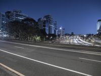 a busy highway with street lights and buildings in the background at night in city center