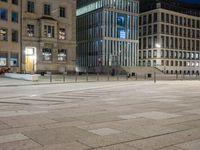 a city at night with street light and buildings and people walking in the street, some standing on brick pavers