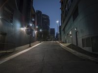 an empty street lined with traffic at night in a city with high rise buildings and many light posts